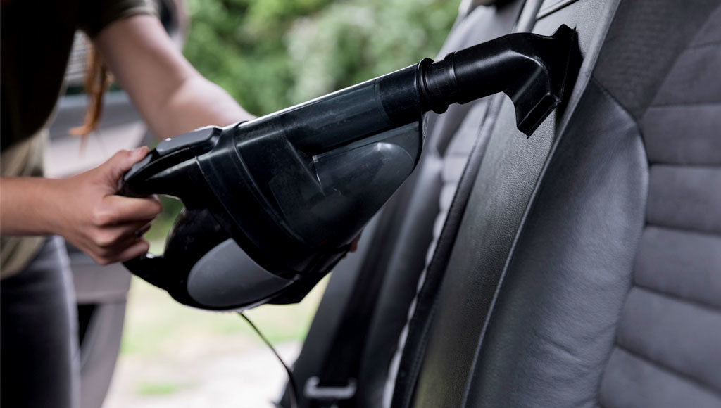 Person vacuuming black leather Porsche interior